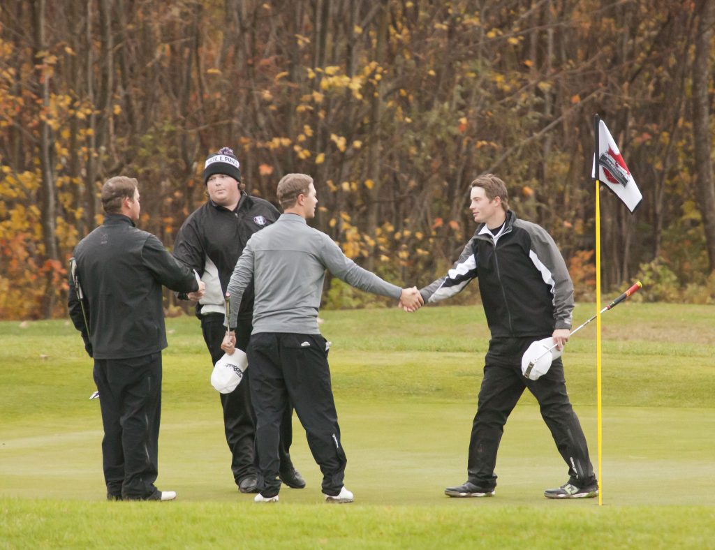 UFV's Zach Olson (left) shakes hands with his opponents following Friday's blustery final round.